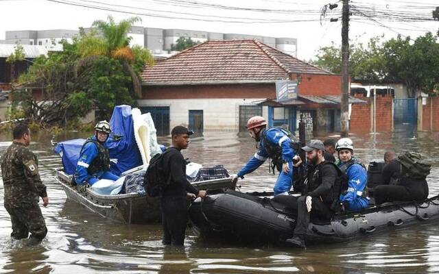 5月10日，救援人员在巴西南里奥格兰德州卡诺阿斯市用船搬运被淹医院的设备和药品。新华社发(卢西奥·塔沃拉摄)