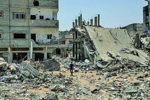    &nbsp5月21日，在加沙地带南部城市汗尤尼斯，巴勒斯坦人经过以军轰炸后的废墟。新华社发