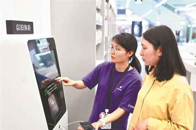重庆市沙坪坝区融创茂商场，市民使用手机回收机器人进行旧手机估价回收。图片来源：视觉中国