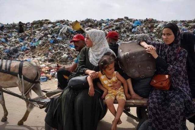 （28日，以色列再次袭击加沙地带南部城市拉法后，巴勒斯坦妇女和儿童带着财物逃离拉法。）