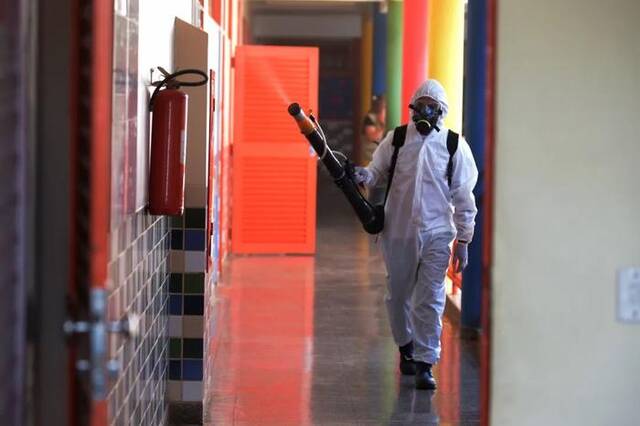 3月9日，在巴西首都巴西利亚一所学校内，公共卫生人员喷洒灭蚊剂。图片来源：新华社发（卢西奥·塔沃拉摄）
