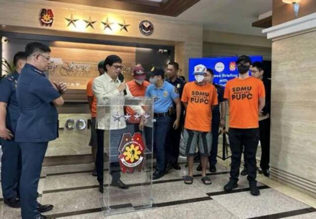 ▲菲律宾内政部长阿巴洛斯（中）宣布，有4名警察因绑架4名外国游客并索要赎金而被捕。图中穿橙色衣服的系犯罪嫌疑人