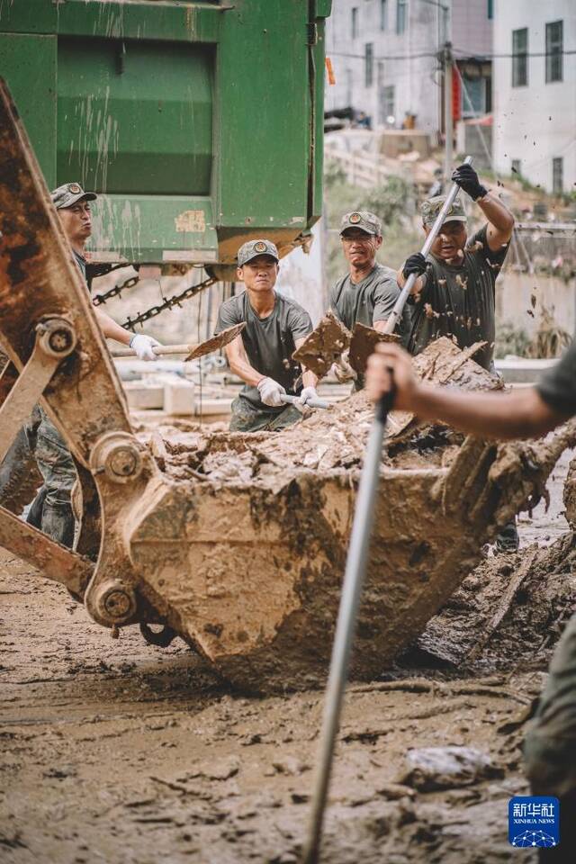 6月20日，福建省军区龙岩军分区民兵在武平县岩前镇清理淤泥。新华社发（李伟君摄）