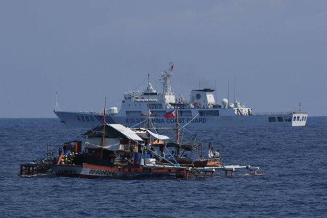 5月16日，菲律宾多艘船只在中国黄岩岛邻近海域非法聚集，中国海警加强监视取证进行现场管制。图为一艘中国海警船驶过一艘菲律宾渔船。视觉中国供图