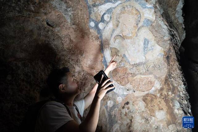 6月15日，在阿富汗巴米扬省，中国学者邵学成在一处石窟中观察壁画。新华社记者赵家淞摄