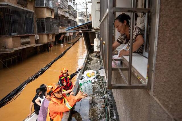 2024年7月2日，在平江县大桥西路附近，消防员给被困群众运送物资。新华社记者陈思汗摄