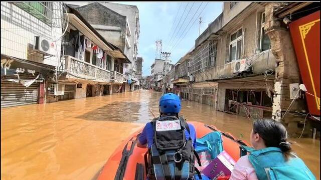 湖南省红十字蓝天救援队的队员载着受灾居民，驾驶冲锋舟撤离。受访者供图