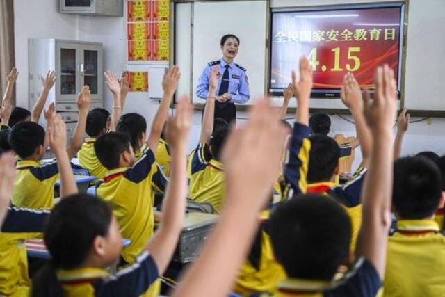 2024年4月15日，在广西兴业县一所小学内，公安民警在讲解国家安全相关知识的过程中与学生们互动。新华社记者曹祎铭摄