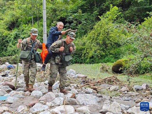 7月21日，在四川省雅安市汉源县马烈乡新华村，武警四川总队雅安支队官兵背着受伤老人穿过乱石河滩。新华社发（刘爽摄）