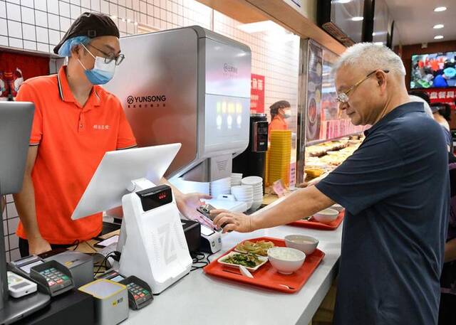 老人正在广州桐乐社区饭堂买单（7月24日摄）。新华社记者李贺摄