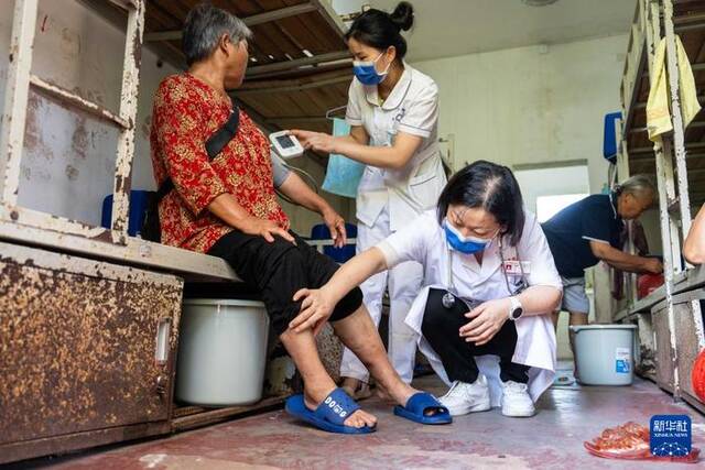 7月30日，在湘潭县河口中学安置点，医务人员为转移安置的群众检查身体。新华社记者陈思汗摄