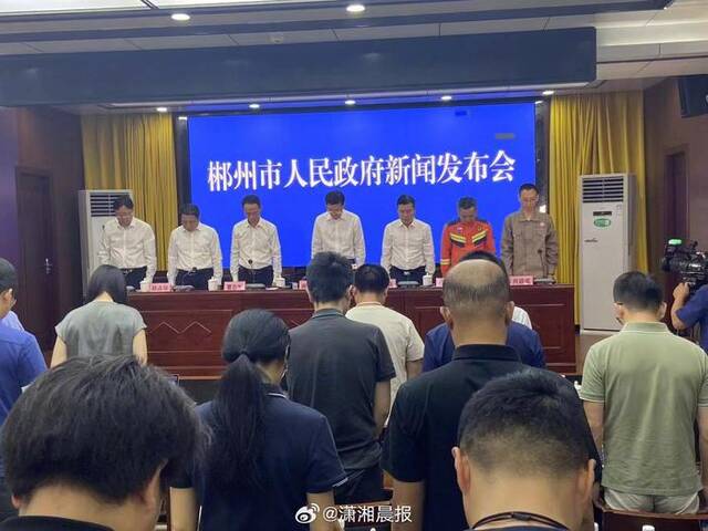 湖南郴州市新闻发布会现场，与会人员起立向特大暴雨遇难者默哀