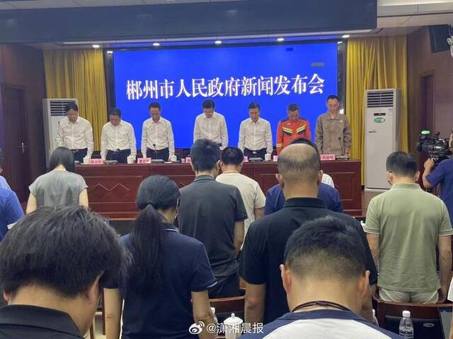 湖南郴州市新闻发布会现场，与会人员起立向特大暴雨遇难者默哀