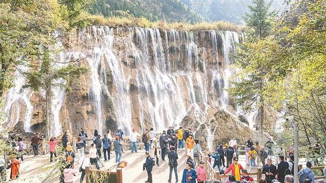 在四川省阿坝藏族羌族自治州，九寨沟景区“高颜值”秋景上线。图为近日，游客在景区内欣赏秋季美景。图片来源：视觉中国