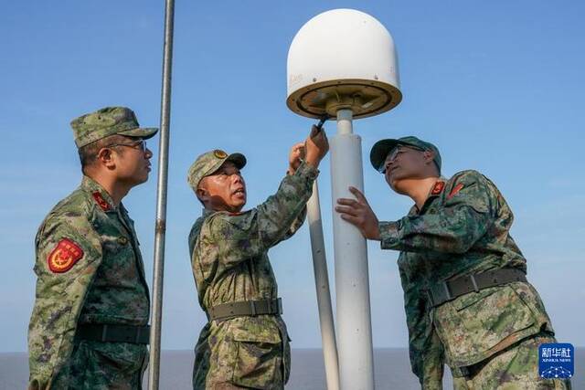 开山岛守岛民兵孙存东（中）、王凯洋（右）、李富明在巡岛路上检查岛上的仪器设备（10月25日摄）。新华社记者李博摄